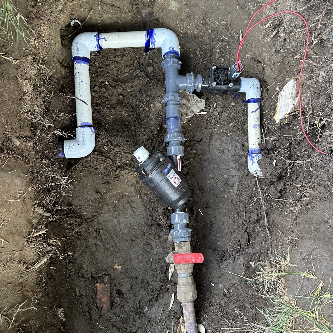 Freshly assembled PVC valve manifold and piping in an open trench